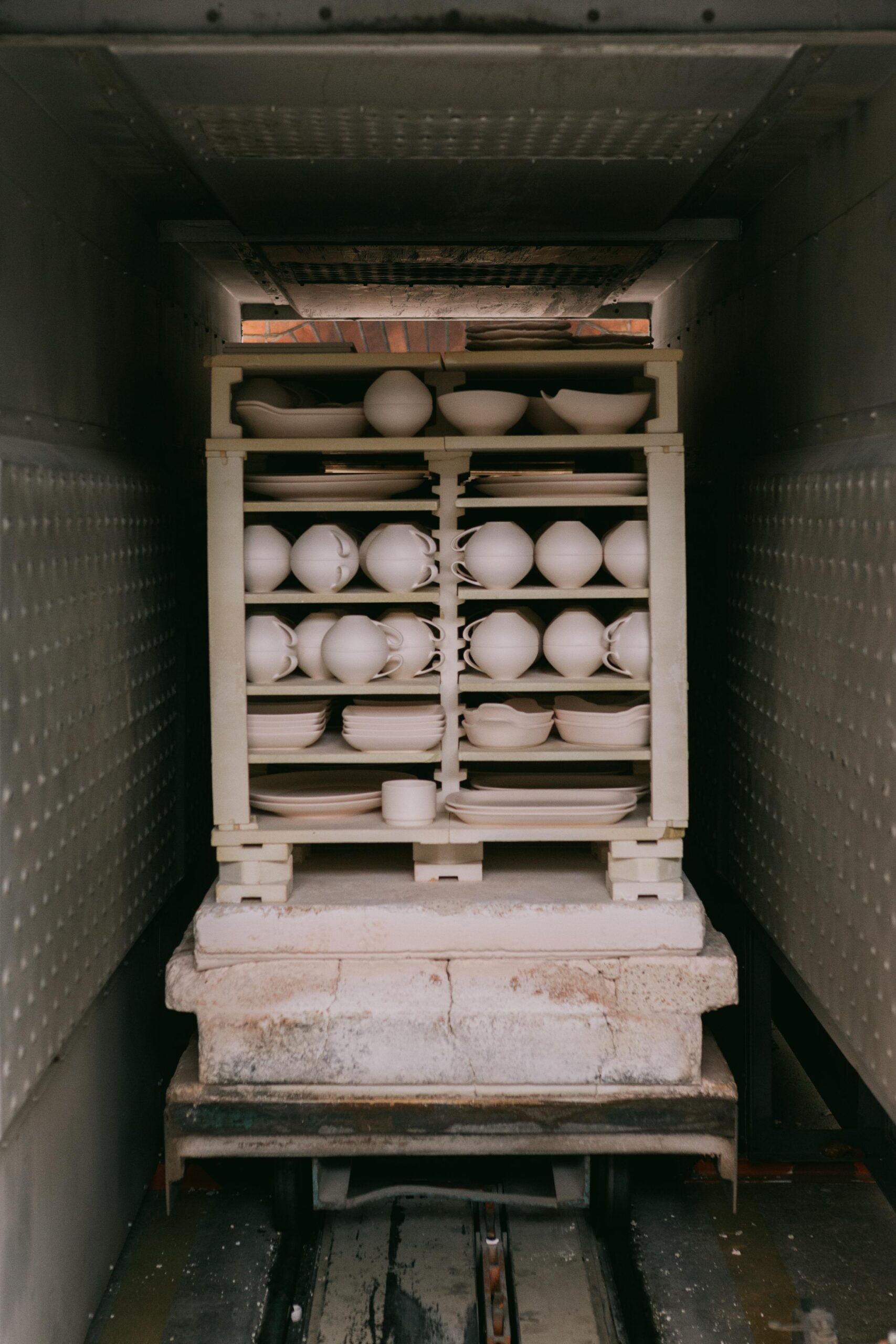 A stack of unglazed ceramic dishes arranged in a kiln for firing, ready for the final process.